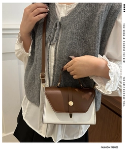 Détail d'un sac bandoulière bicolore avec boucle en métal et poignée sur un mannequin