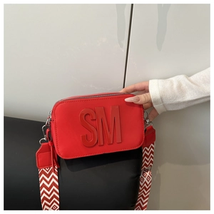 Dettaglio della borsa a tracolla in pelle rossa con logo SM a rilievo e tracolla larga