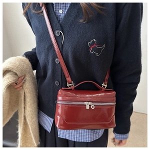 Detail of red patent leather mini bag paired with a navy cardigan and striped shirt