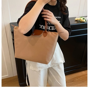 Détail du sac cabas en nylon kaki avec rabat en cuir marron et fermeture éclair sûre