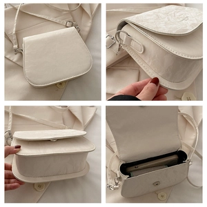 Detail view of cream saddle bag featuring marble texture and adjustable shoulder strap