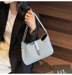 Detail of light blue woven underarm bag with silver buckle and chain leather strap