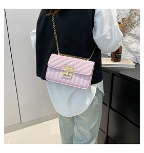 Detailed view of pink quilted patent leather crossbody bag with gold H-buckle on model