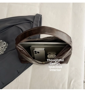 Detailed view of dark brown tote bag interior housing a laptop and smartphone