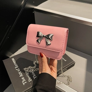 Pink crossbody square bag with silver metal bow and delicate chain strap shown in hand