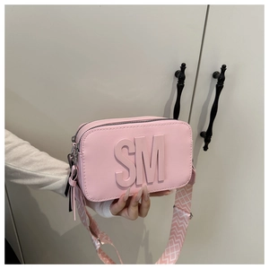 Dettaglio della borsa rosa con logo SM a rilievo e tracolla larga a motivi geometrici