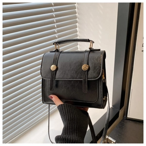 Detail of vintage black faux leather handbag with wax finish and golden round metal buckles