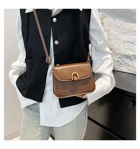 Detailed view of brown vintage leather saddle bag with gold horseshoe buckle on model