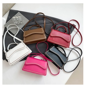 Detailed overhead view of minimalist square handbags with unique wavy flap and gold stitching