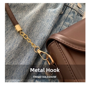 Detail of dark brown leather handbag featuring gold metal hooks and stitching