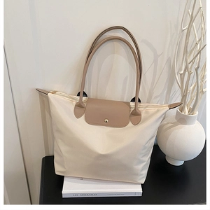 Détail d'un grand sac cabas en nylon crème avec anses en cuir marron et fermeture éclair