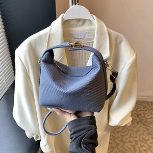 Navy blue knitted pillow bag with gold clasp and top handle for versatile crossbody styling