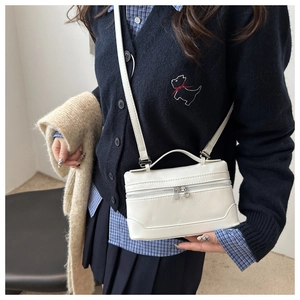 Detailed view of a white rectangular crossbody bag with silver hardware on a model