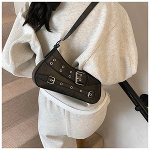 Detail of black punk shoulder bag with silver grommet straps and vintage leather texture