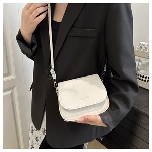 Detail of white saddle bag with FASHION TREND lettering and textured faux leather finish