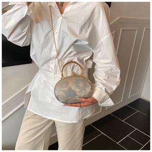 Detail of grey embroidery handbag with gold floral pattern and metal handle