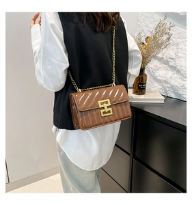 Detail of caramel brown glossy crossbody bag with quilted texture and golden H-lock