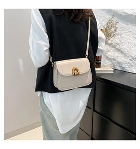 Detail of beige faux leather handbag featuring a stylish gold U-shaped metal lock closure