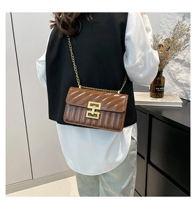 Close-up of brown quilted chain bag with gold hardware on a stylish modern outfit
