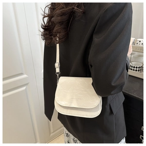 Macro detail of white saddle bag showing textured faux leather and metal buckle finish