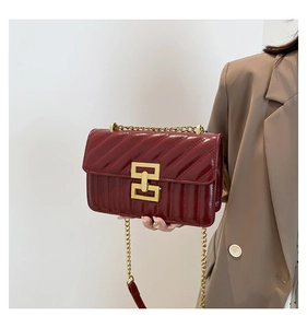 Close-up of wine red quilted leather shoulder bag with elegant gold chain and metal lock