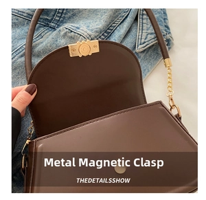 Detail showing the magnetic hardware closure on a dark brown leather crossbody bag