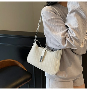 Detail of cream woven underarm bag with silver chain strap and metal buckle closure