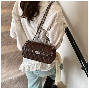 Quilted dark brown crossbody bag with chain strap shown on model in stairwell