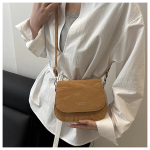 Detail of a brown saddle bag featuring unique pleated texture and adjustable strap