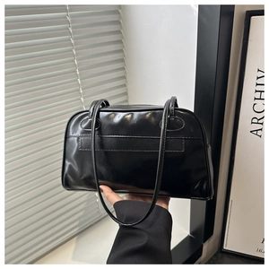 Dettaglio borsa bowling nera lucida con cuciture minimaliste e sottili manici a spalla