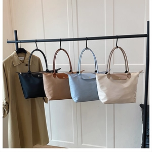 Détail de quatre sacs fourre-tout en nylon de couleurs avec poignées en cuir sur support