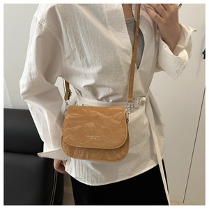 Close-up of khaki crossbody saddle bag with wrinkled texture and fashion lettering