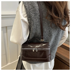 Détail d'un sac bandoulière en cuir marron foncé avec fermetures éclair argentées