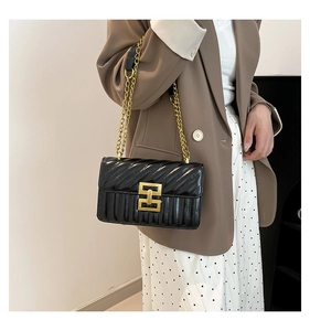 Close-up of black quilted chain crossbody bag with golden hardware and square buckle