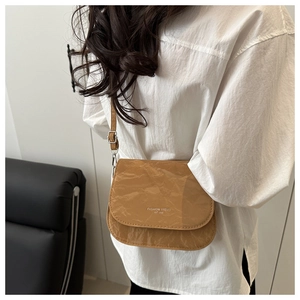 Detail of caramel saddle bag with crinkled leather texture and fashion trend lettering