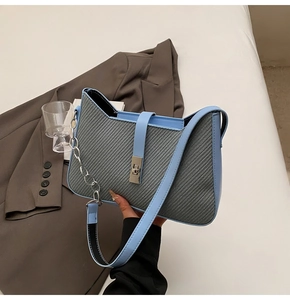 Close-up of the grey twill fabric texture and blue leather trim with a silver metal lock