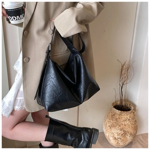 Detail of black pleated shoulder bag showing glossy texture and large capacity style