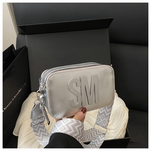 Dettaglio borsa a tracolla argento con logo SM e tracolla larga con motivo geometrico moderno