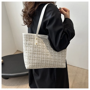 Detail of tweed tote bag side silhouette with gold thread texture and leather strap