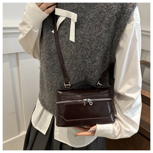 Détail du petit sac carré en cuir verni marron foncé avec double fermeture éclair