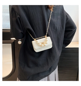 Detailed view of white mini pearl bag with crocodile pattern and gold chain strap