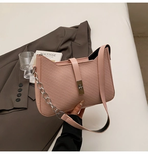 Detail of pink twill textured underarm bag with silver chain and metal twist lock