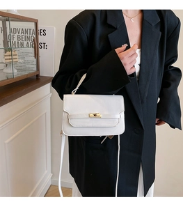 Detail of white glossy leather handbag with gold twist-lock and slim shoulder strap