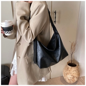 Détail du sac cabas en similicuir noir souple montrant la texture grainée et la bandoulière