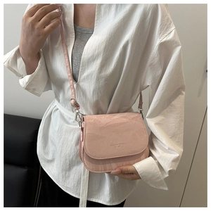 Detail of pink saddle bag with crinkle texture and Fashion Trend embossed lettering