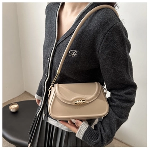 Detail of glossy beige patent leather bag featuring a gold multi-ring metallic clasp