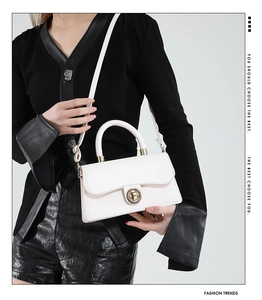 Détail d'un sac à main blanc en cuir avec fermoir doré rotatif et design raffiné
