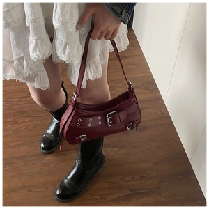 Detail of burgundy leather shoulder bag with silver buckles and metallic eyelets