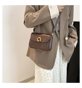 Detail of vintage brown oil leather saddle bag featuring a polished gold semicircular lock