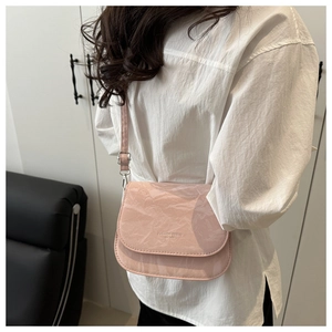 Detail of pink crinkled patent leather saddle bag with silver buckle and logo print